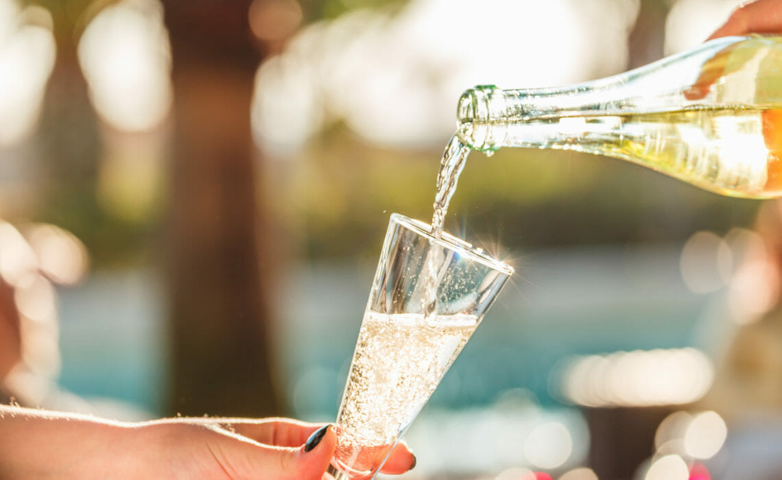 Pouring Prosecco sparkling wine into a glass, on a summer day