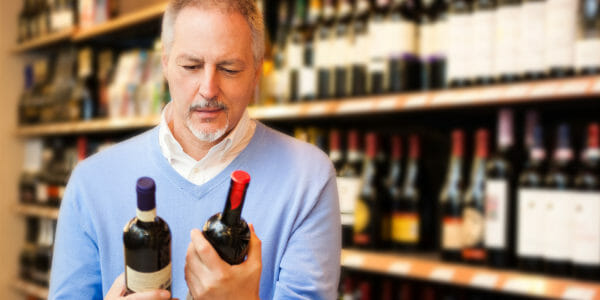 Consumer looking at inexpensive wine in supermarket