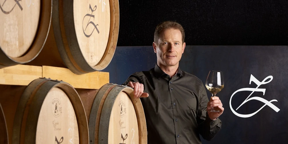 Peter Zemmer tasting white wine in his cellar with oak barrels, in Cortina, Alto Adige