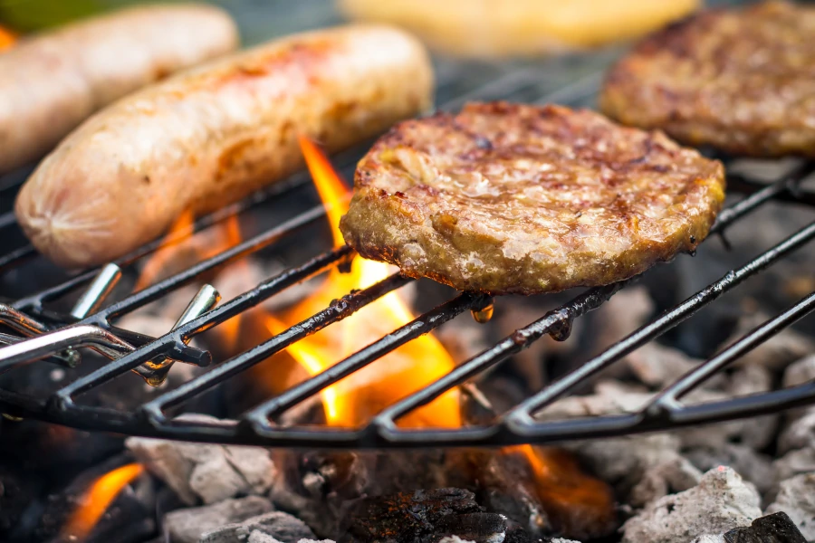 Burgers and Sausages frying on barbeque grill