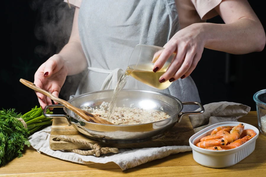 Female Chef Cooking Risotto with White Wine and Tiger Shrimps