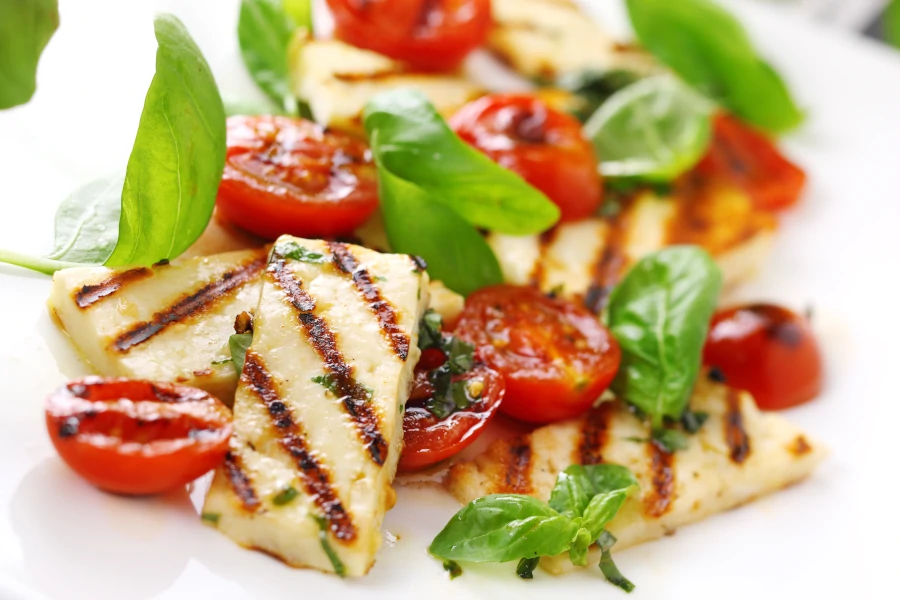 Fried Halloumi cheese with cherry tomatoes, spices and basil leaves