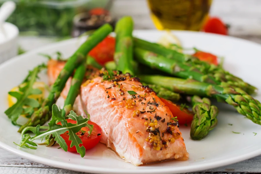 Fried salmon steak with asparagus, cherry tomatoes and rocket salad