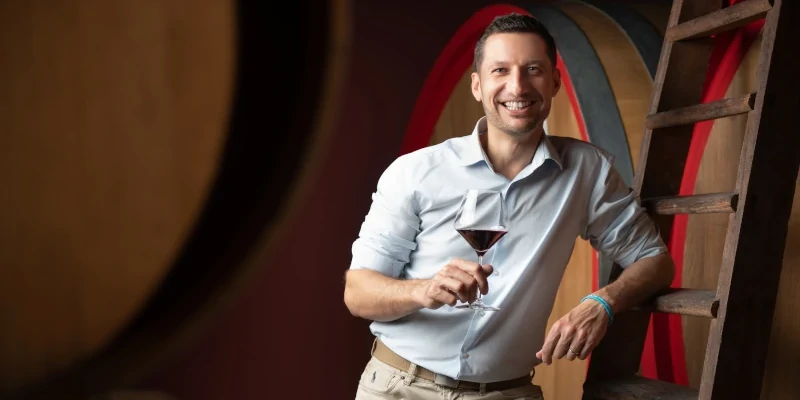 Paolo Demarie holding a glass of Barolo in the ageing cellar of Demarie wienry in Vezza d'Alba, Piemonte, Italy