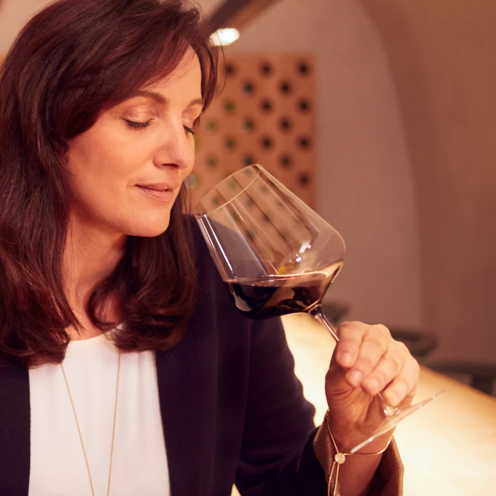 Lady tasting red wine from a large glass in Alto Adige, wine tourism