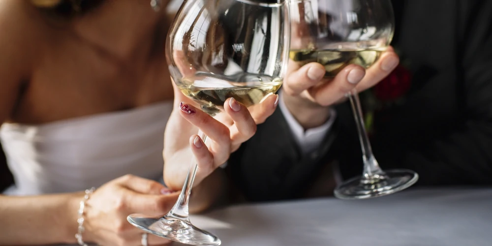 Bride and groom drinking white wine, wedding party
