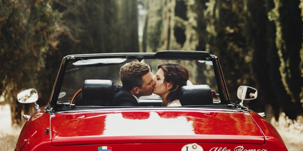 Bride and groom in a red Alfa Romeo in Tuscany, Italian wedding