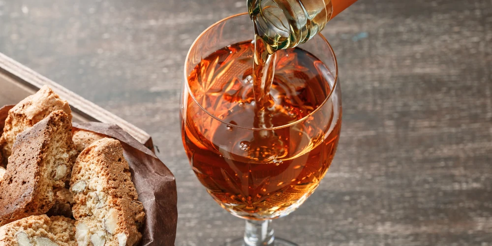 Vin Santo dessert wine poured into glass and cantucci almond cookies